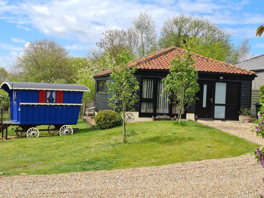 ein winziges Haus mit einem blauen Schuppen daneben. in der Unterkunft Inviting 2 bedroom barn conversion rural Norfolk in Loddon