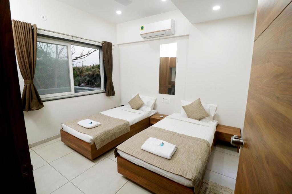 a room with two beds and a window at Nova Sahaj Residency in Khirasra
