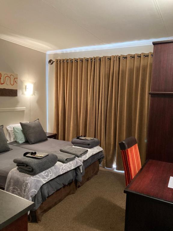 a hotel room with two beds and a desk at Unit 14 A-Block Bains Game Lodge in Bloemfontein