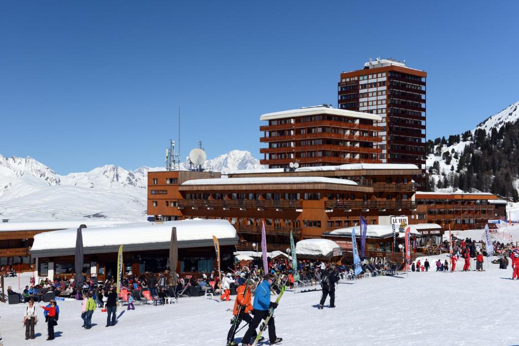 a group of people skiing in the snow in front of a building at Résidence Odalys Le Pelvoux in La Plagne
