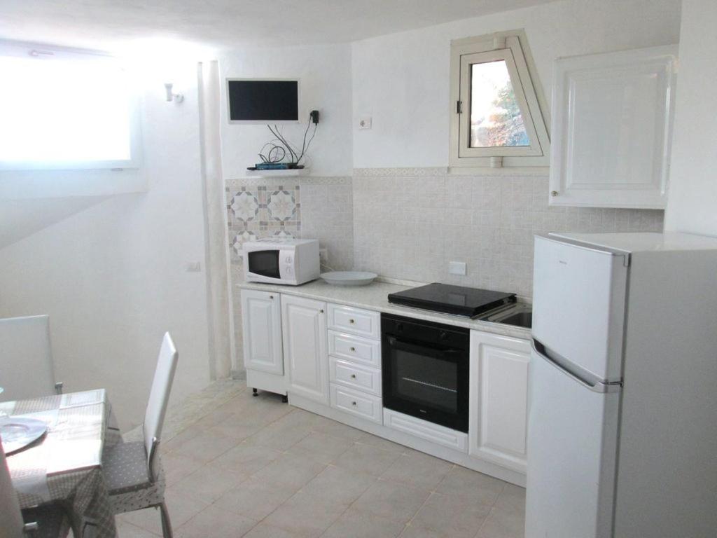 a kitchen with white cabinets and a white refrigerator at Sardinia Yellow House in Solanas