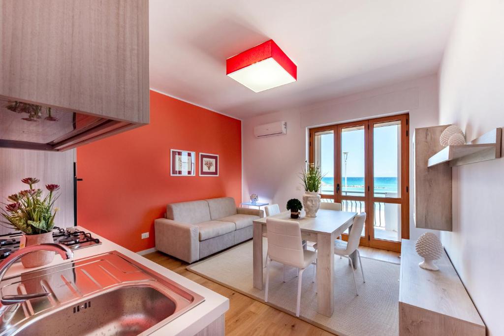 cocina y sala de estar con paredes de color naranja y mesa. en Appartamenti fronte mare Otranto, en Otranto