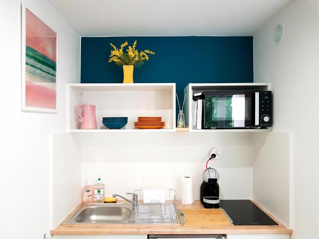 eine Küche mit einer Spüle und einer Mikrowelle in der Unterkunft Joli studio rénové en bord de mer in Bormes-les-Mimosas