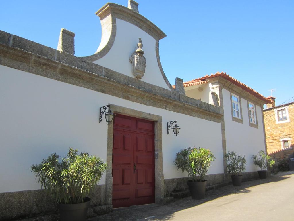 a red door on a white building with plants at Quinta das Aranhas in Castelo de Paiva