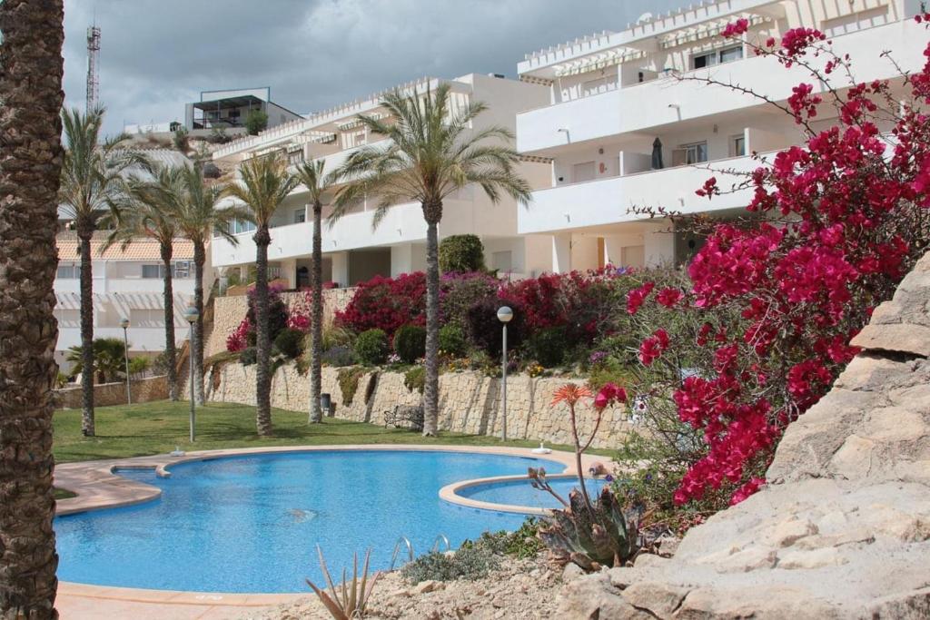 un complejo con piscina, palmeras y flores rosas en Casa Mediterranea, en Relleu
