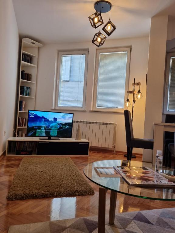 uma sala de estar com uma televisão e uma mesa de vidro em Apartman Veselinovic Free PARKING em Vranje