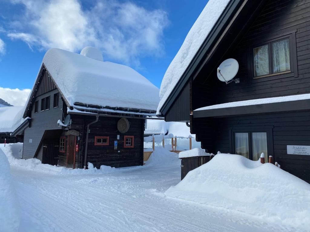a snow covered house with a pile of snow next to it at Stubihuettn in Sonnenalpe Nassfeld