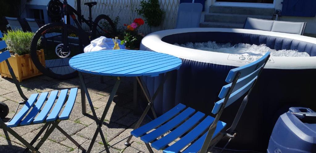 una mesa azul y sillas junto a una bañera de hidromasaje en Gîte La petite maison horlogère et jacuzzi , raquettes en Les Fontenelles