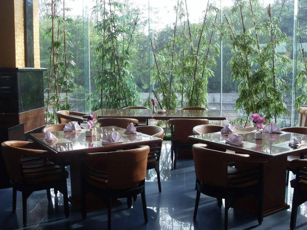 a restaurant with tables and chairs and a large window at Hotel Oval in Surabaya