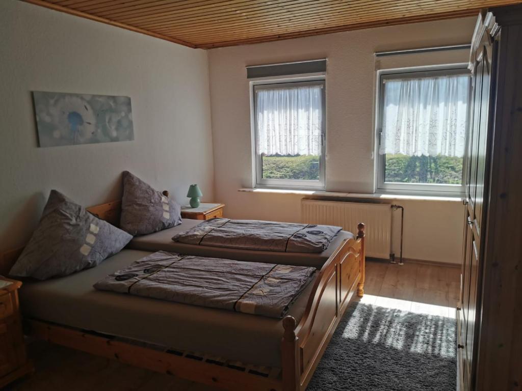 MürlenbachにあるFerienhaus Johannのベッドルーム1室(ベッド2台、窓2つ付)