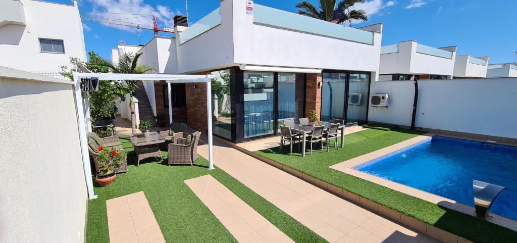 a white house with a swimming pool and a yard at Lo Pagan Holiday House in San Pedro del Pinatar