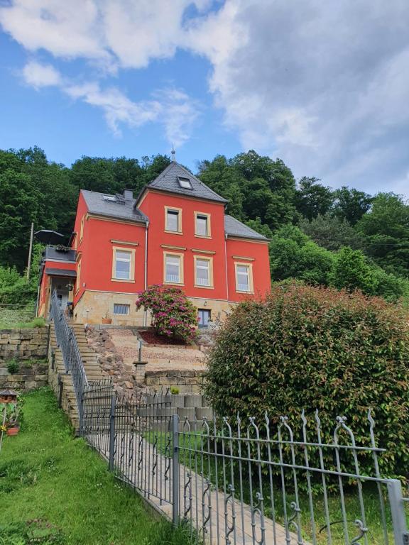 ein rotes Haus mit einem Zaun davor in der Unterkunft Ferienwohnung "Möller" in Rathmannsdorf