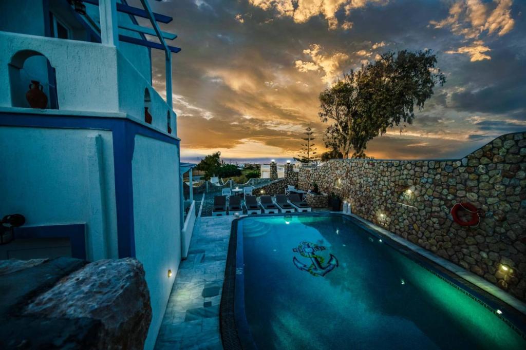 a swimming pool in front of a building with a sunset at Stavros Villas in Karterados