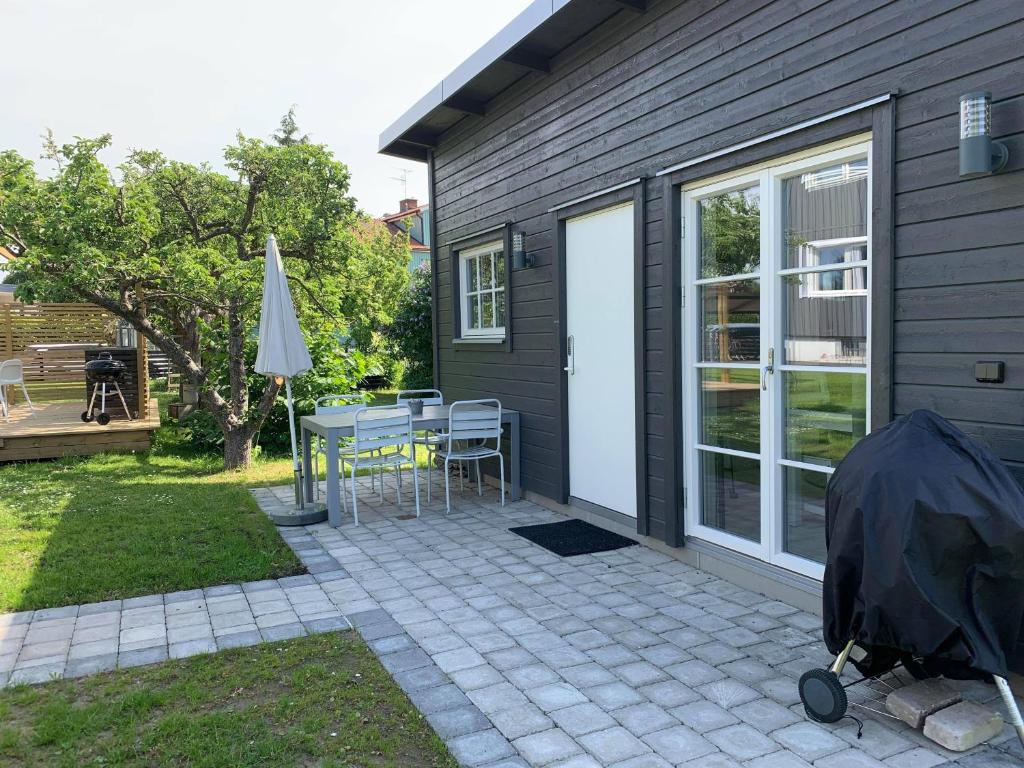 a patio with a table and an umbrella and a house at Toppmodernt litet hus nära Kalmar slott och havet in Kalmar