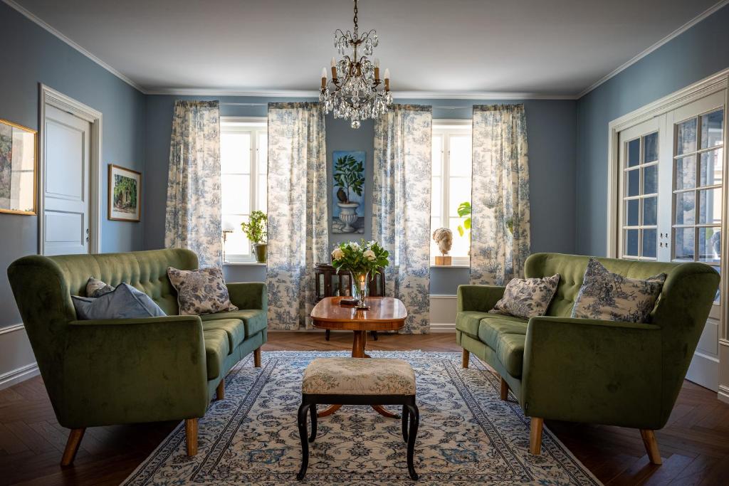 a living room with two green couches and a table at Fregatten Bed & Breakfast in Karlskrona