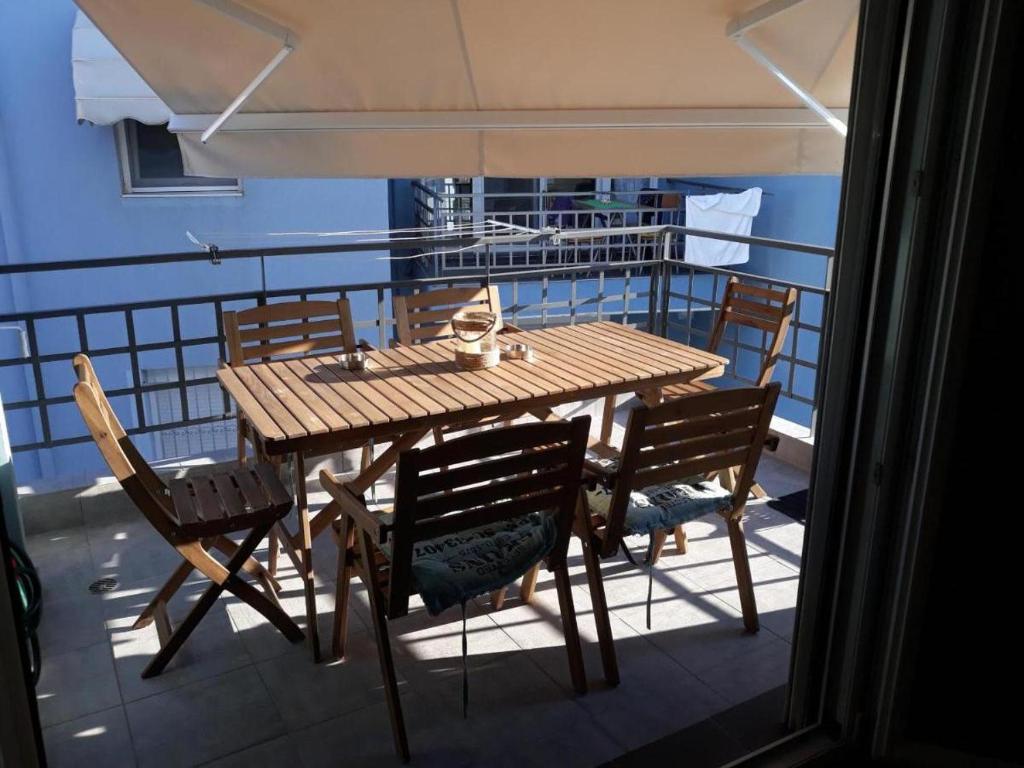 ein Holztisch und Stühle auf einem Balkon in der Unterkunft Τhe Diamond in Néa Péramos