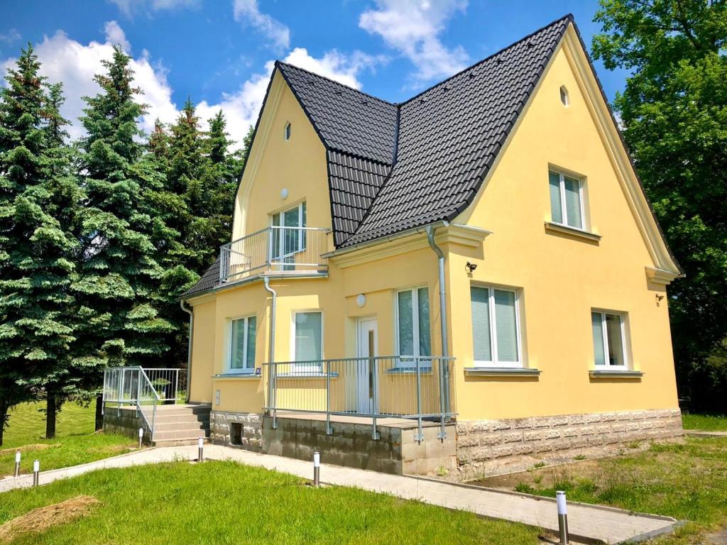 une maison jaune avec un toit noir dans l'établissement Apartmány Zahrádky, à Hráz