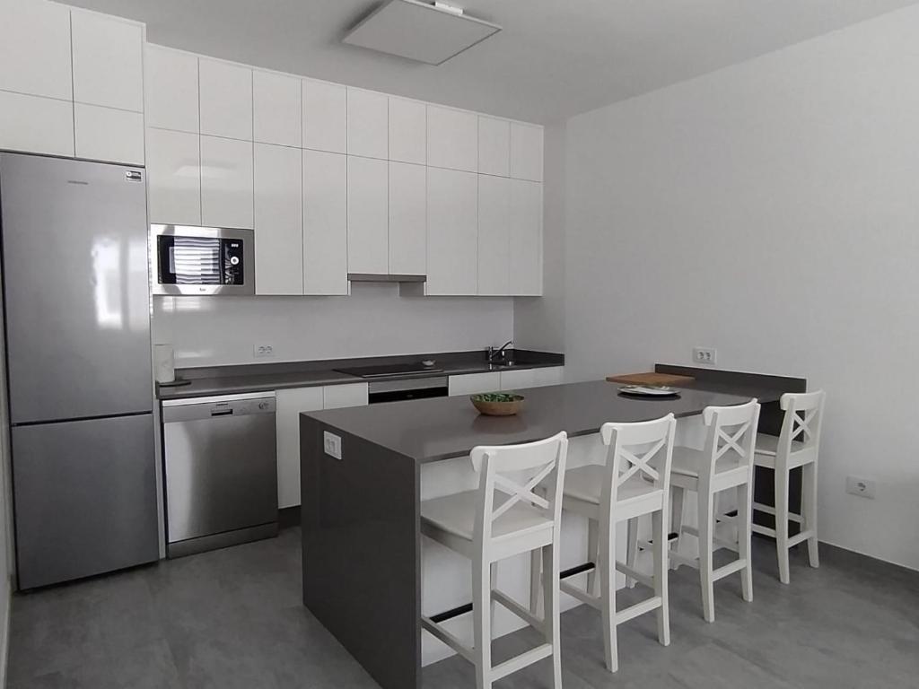 a kitchen with white cabinets and a counter with white stools at Casa Blanca La Restinga in La Restinga
