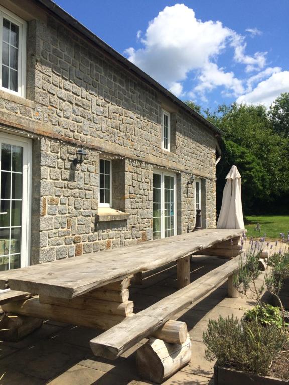 una panca di legno di fronte a un edificio in pietra di Holiday home La Ransonniere de Bas a Romagny
