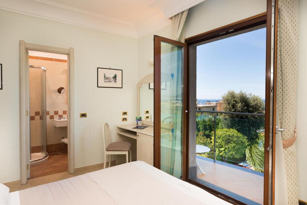 una camera da letto con una grande porta a vetri che conduce a un balcone di Hotel Gardenia Sorrento a Sorrento