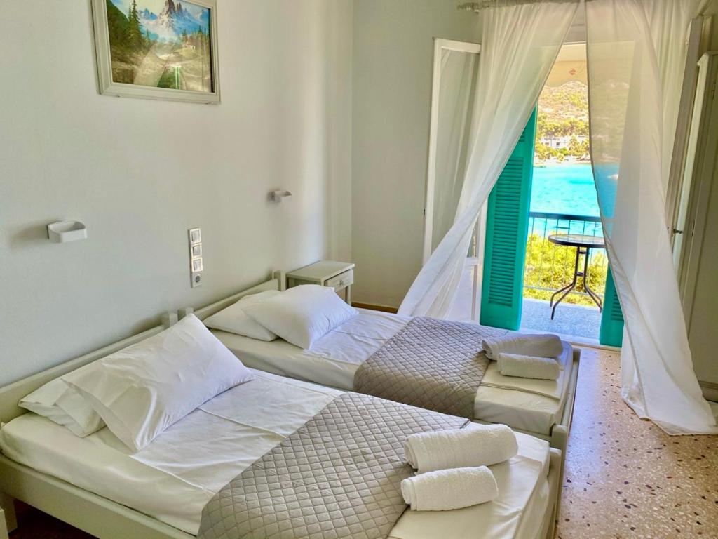 two beds in a bedroom with a view of the ocean at Studios Argyris in Poros