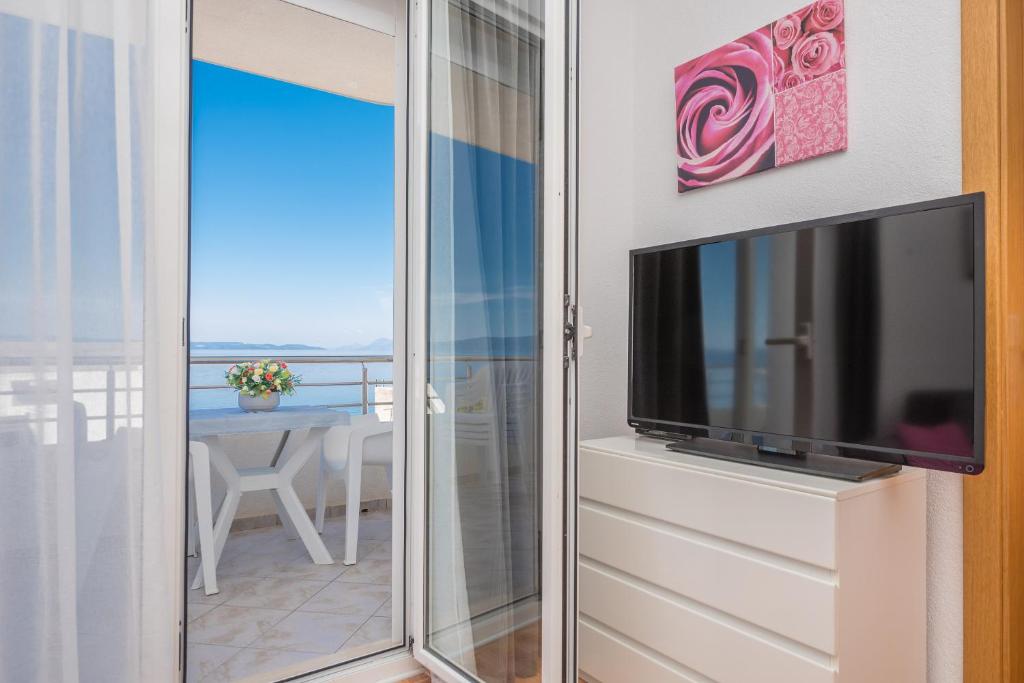 una puerta corredera de cristal que da a un balcón con TV en Apartments Tila, en Drasnice