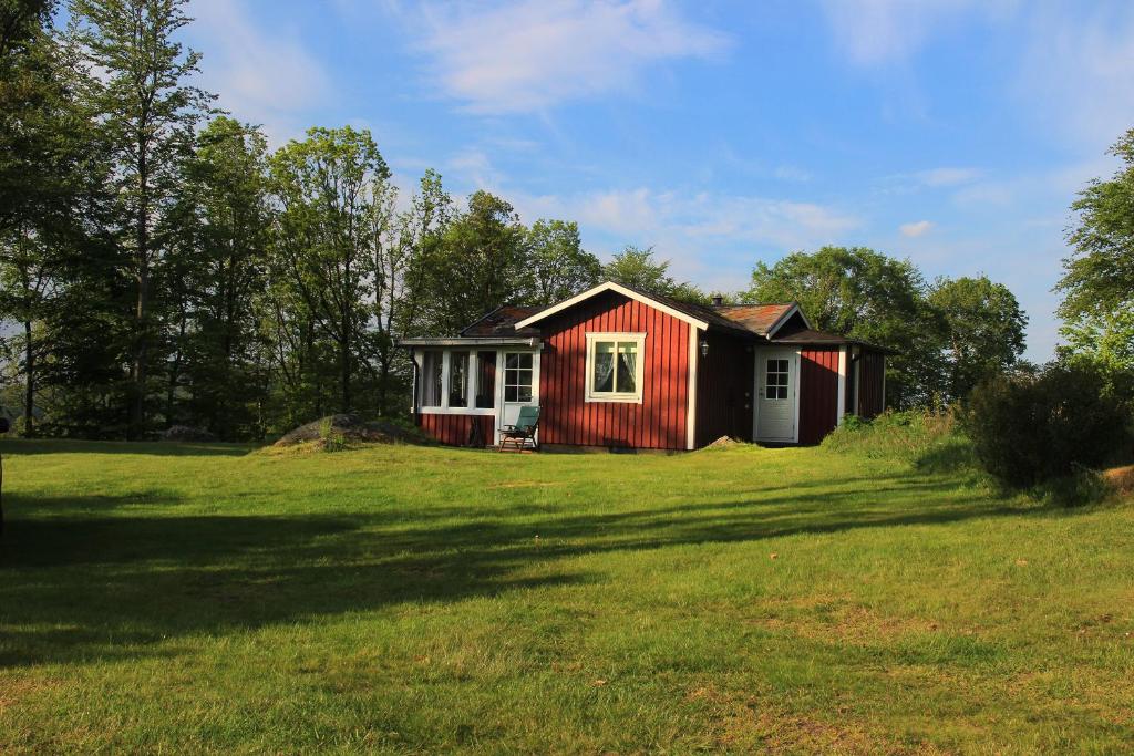 una pequeña casa roja y blanca en un campo en Inga-Majs stuga en Tvååker