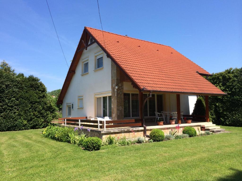een huis met een oranje dak op een groen veld bij Frankie Holiday Apartment I. in Balatongyörök