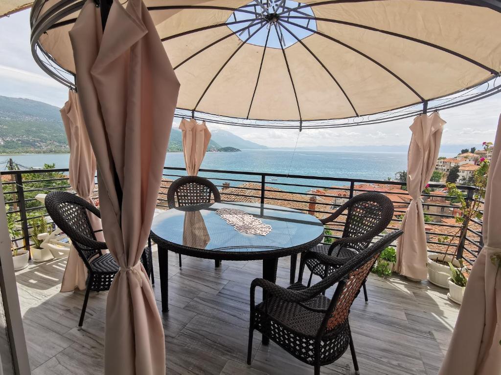 a table and chairs on a balcony with an umbrella at Apartment Ain Naum in Ohrid