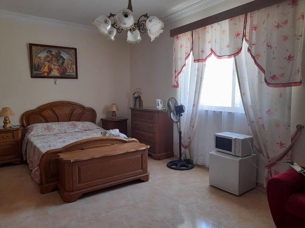 a bedroom with a bed and a television and a window at Private room in Qormi