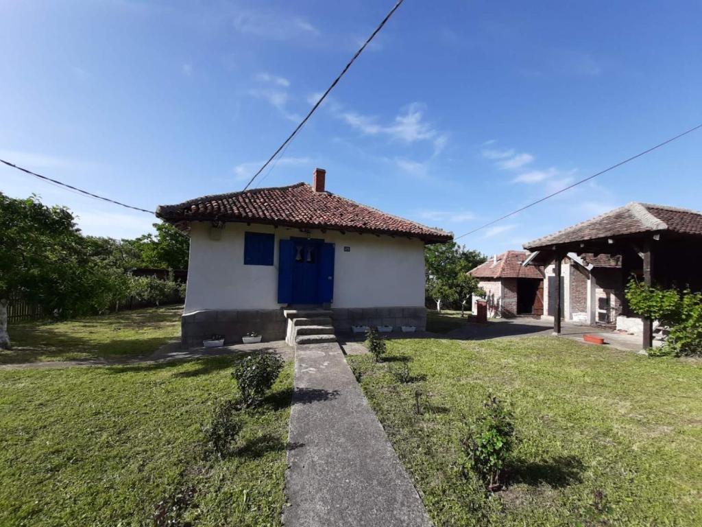 uma pequena casa com uma porta azul num quintal em Etno Selo Dimitrijevic em Arandjelovac