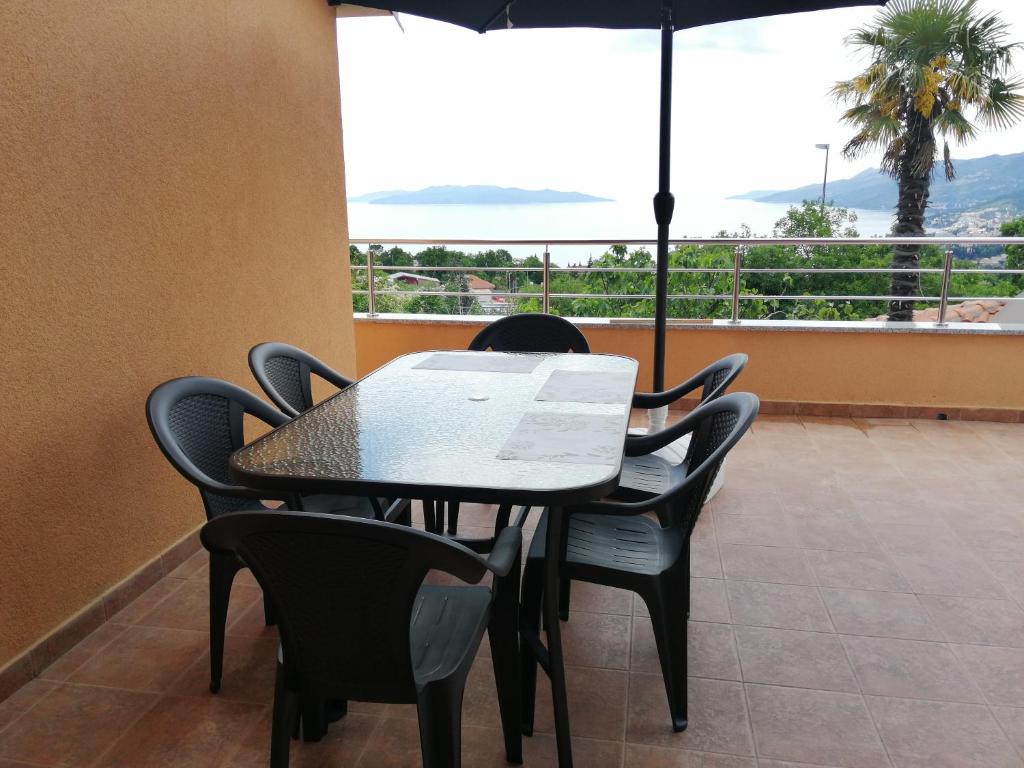 a dining room table with chairs and an umbrella at Appartamento Artur in Matulji