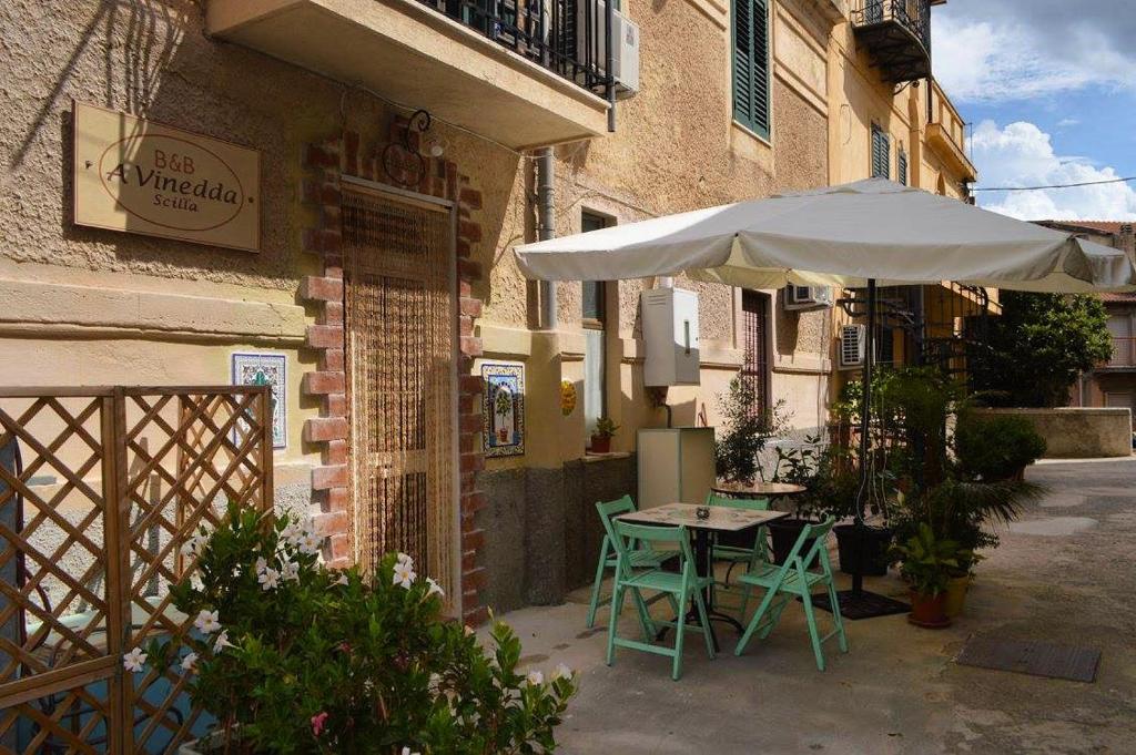 een tafel en een paraplu buiten een gebouw bij Scilla A Vinedda in Scilla