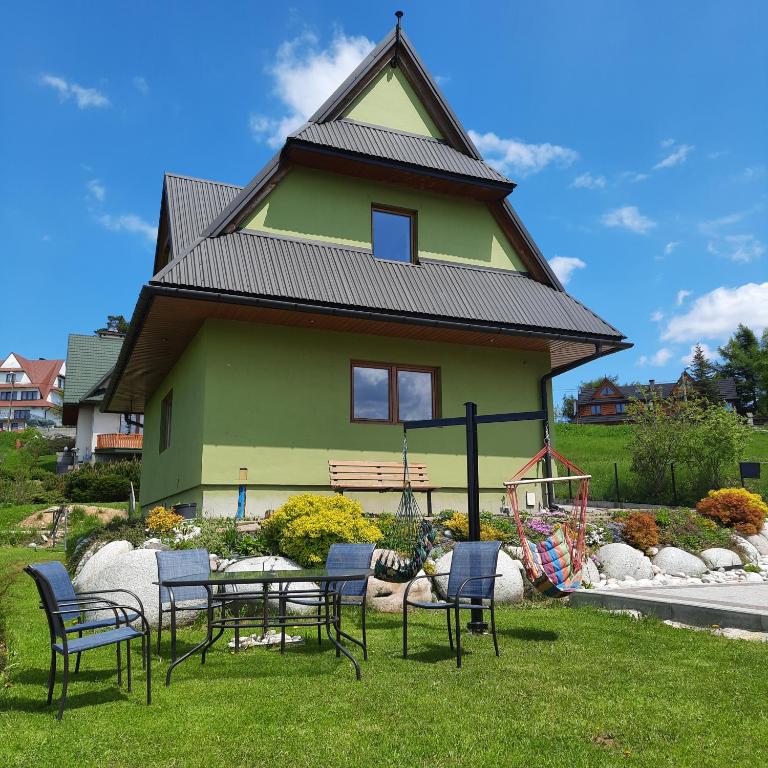 a house with a table and chairs in front of it at Tu i Teraz - domek in Bukowina Tatrzańska