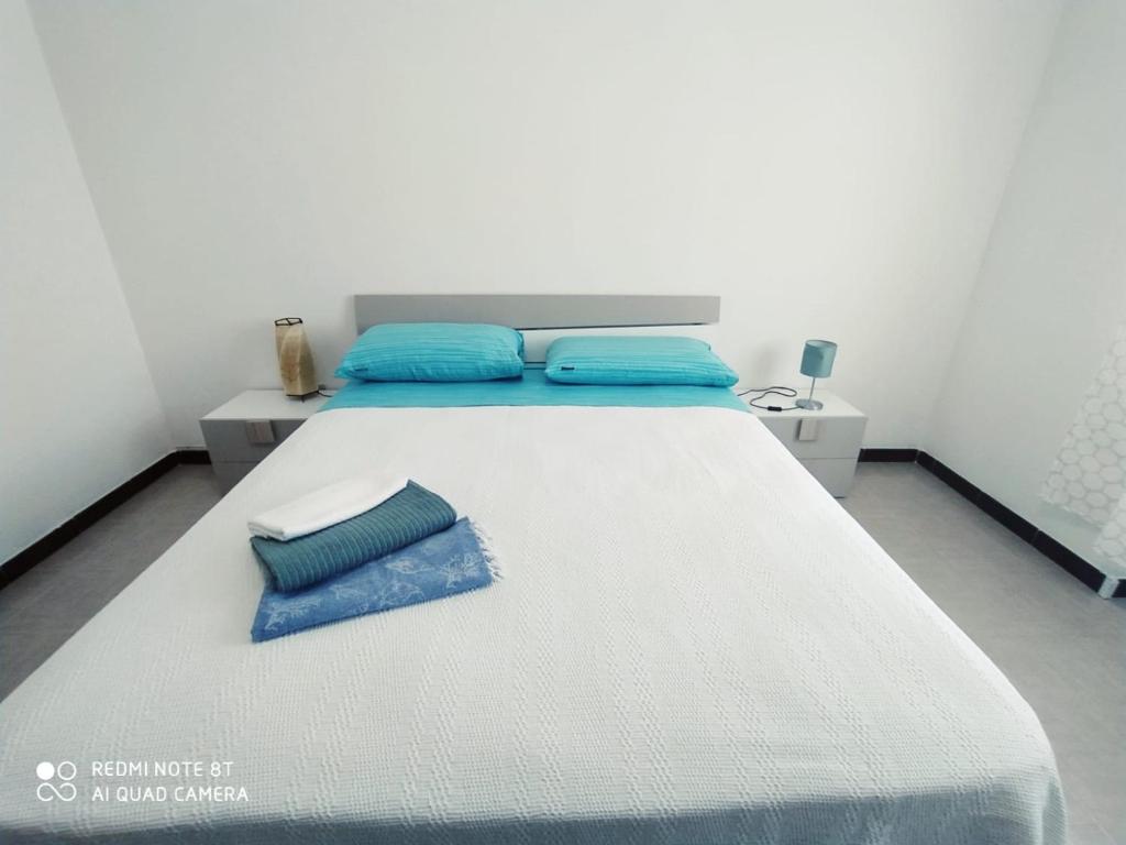 a white bed with blue pillows on top of it at APPARTAMENTO SANTUCCI in Rodi Garganico