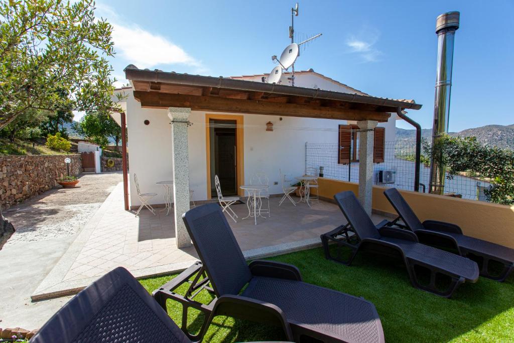 une terrasse avec des chaises et une table ainsi qu'une maison dans l'établissement La Casa in Collina - affittacamere con vista mare, à Lu Lioni