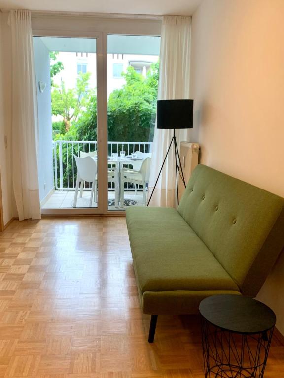 a living room with a green couch and a balcony at Appartement Lilienthal in Klagenfurt