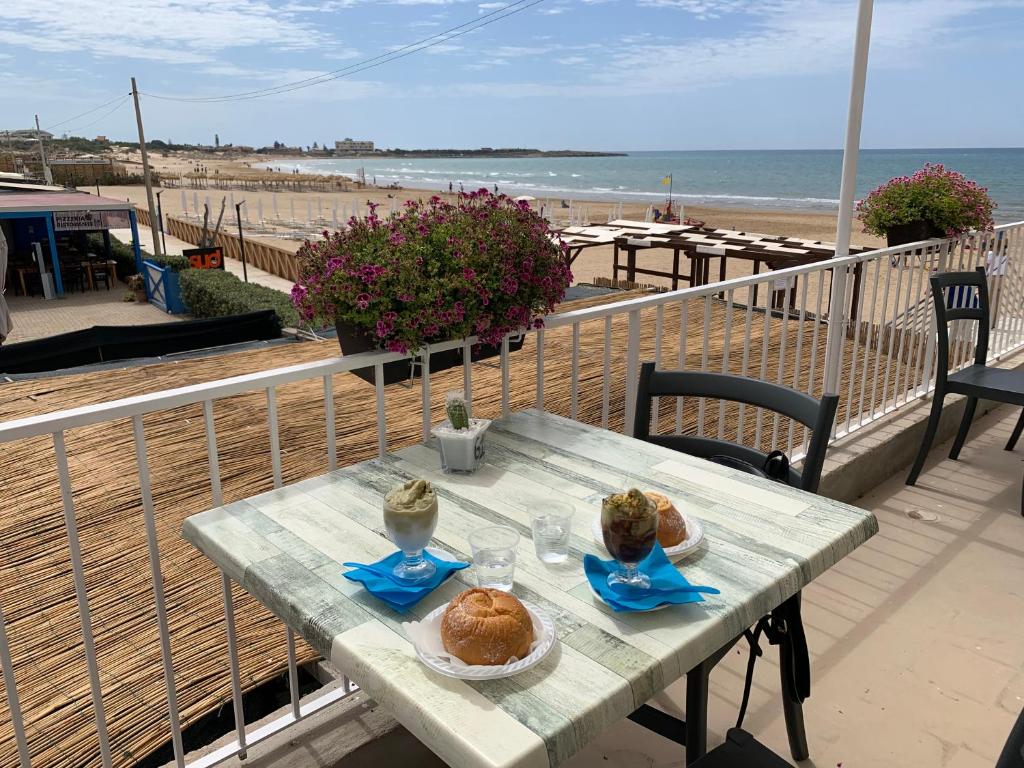 einen Tisch mit Essen auf dem Balkon mit Strand in der Unterkunft Andrea's Home in Marina di Modica