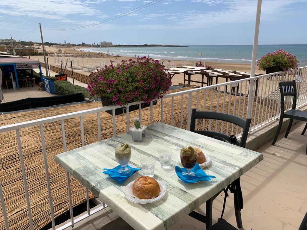 un tavolo con del cibo sopra un balcone con una spiaggia di Andrea's Home a Marina di Modica