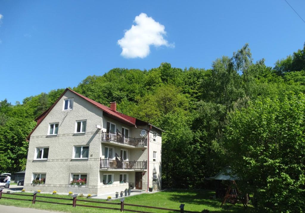 un gran edificio gris con un balcón frente a los árboles en Dom nad potokiem - pokoje całoroczne, en Wołkowyja