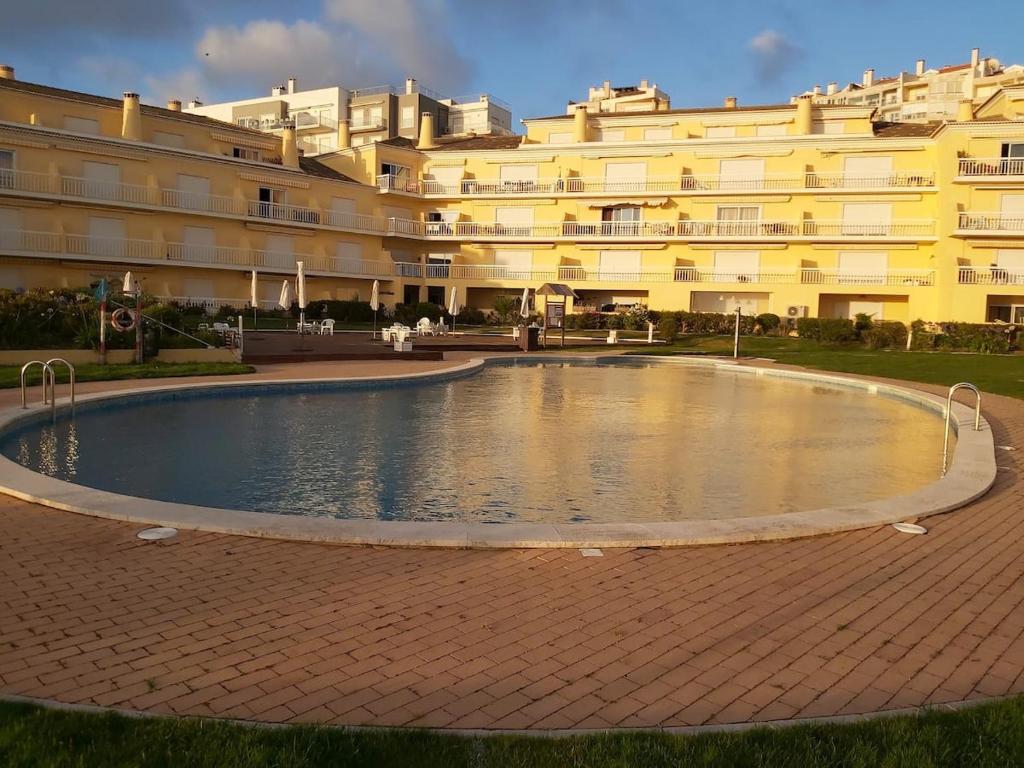 a swimming pool in front of a large building at Sunset Village Apartment - Brisa Da Ericeira in Ericeira