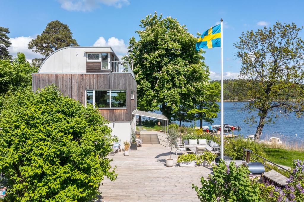 a house on the shore of a lake with a flag at 4 Bedroom Archipelago Retreat in Tranholmen