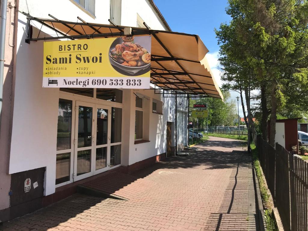 a sign for a restaurant on a street at Sami Swoi in Mielno