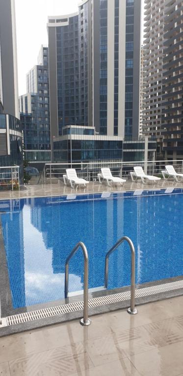 a large swimming pool with white chairs and buildings at New Wave 1 in Batumi