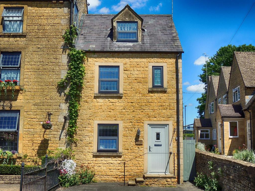 a brick house with a white door and windows at Oakey Cottage in Bourton on the Water