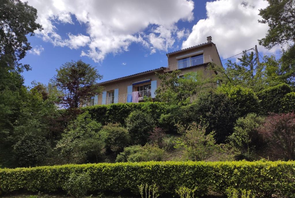 uma casa no topo de uma colina com arbustos em La clairière em Pierrelongue