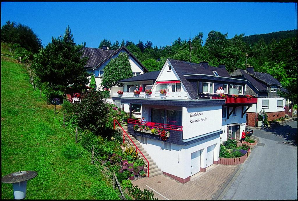 une grande maison blanche avec des fleurs sur le balcon dans l'établissement Gästehaus Kramer - Emde, à Willingen