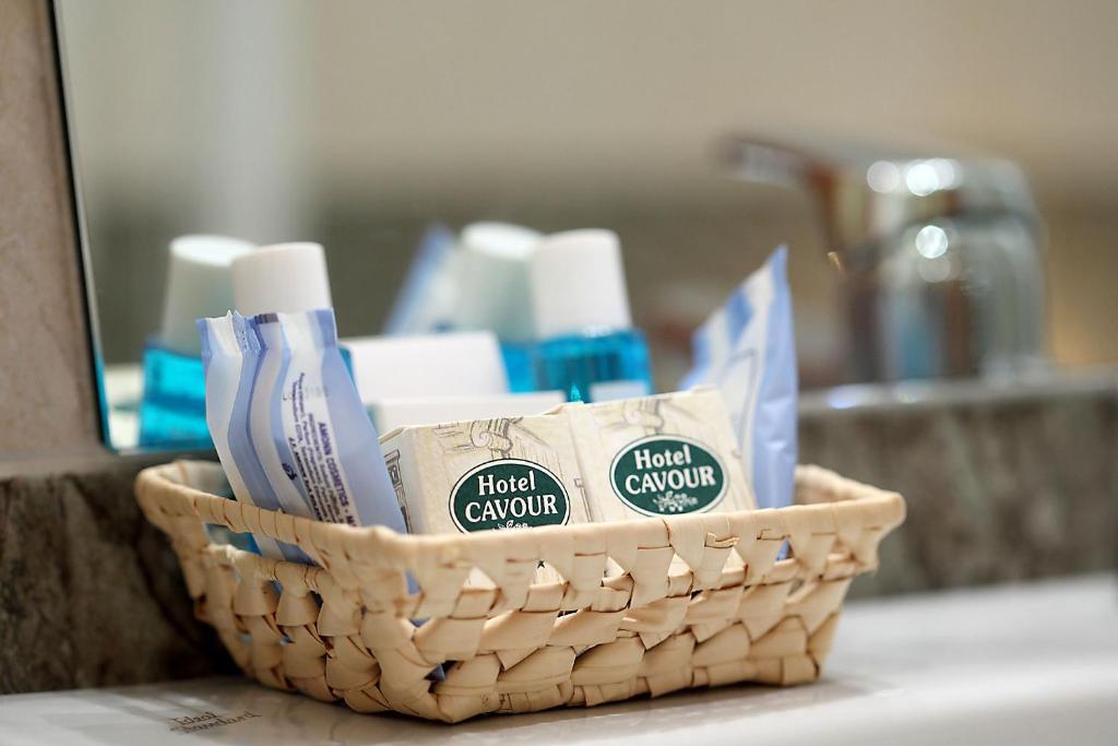 a basket of toothbrushes and toothpaste on a bathroom counter at Hotel Cavour in Rapallo