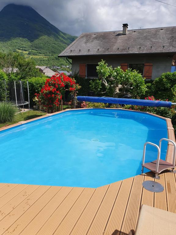 ein blauer Pool mit einem Stuhl und ein Haus in der Unterkunft Chez Gilles et Eveline in Cruet