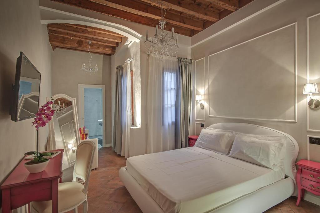 a bedroom with a white bed and a table and chairs at Residenza d'epoca Borgo Albizi in Florence